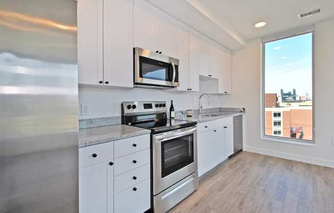 a kitchen with white cabinets and stainless steel appliances and a window