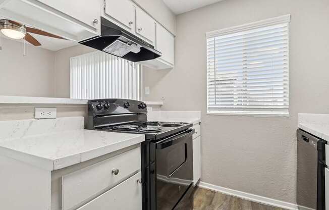 B6 kitchen with a black stove top oven and white cabinets at Windridge on the Parkway in Dallas, TX