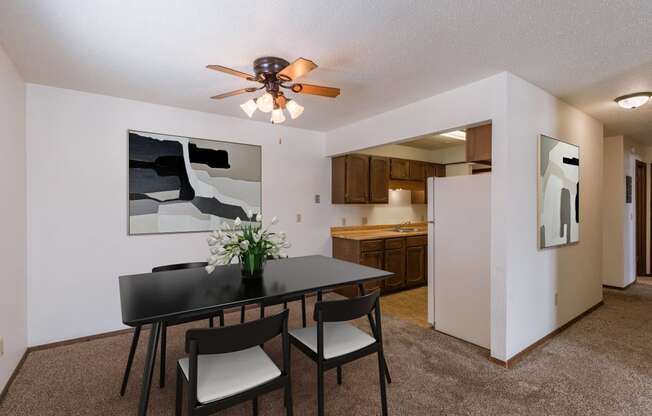 a dining area with a table and chairs and a ceiling fan. Fargo, ND Plumtree Apartments