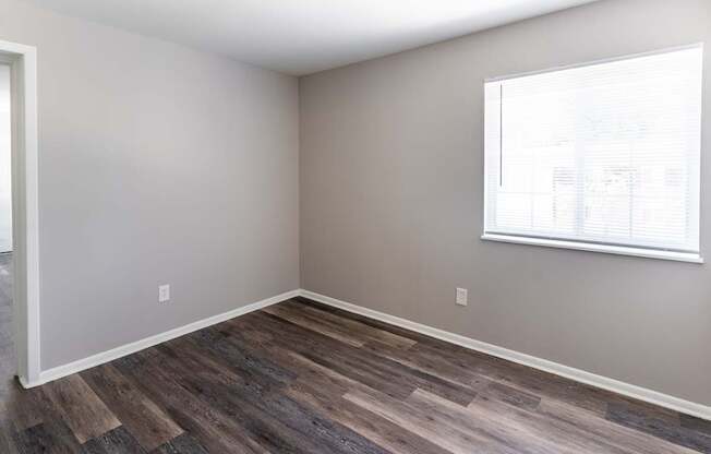an empty room with wood floors and a window