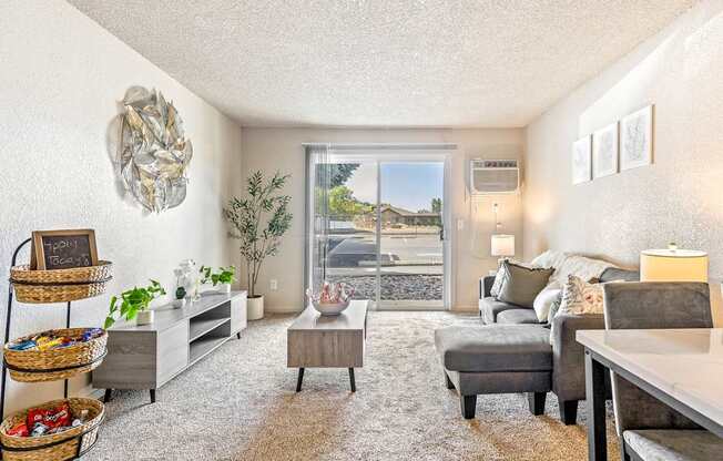 A living room with a grey couch and a white wall t Wildflower Apartments in Kennewick, WA.