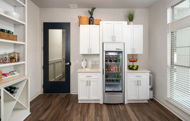 a kitchen with white cabinets and a refrigerator and a door