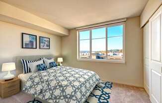 A bedroom with a large bed and a window overlooking a cityscape.