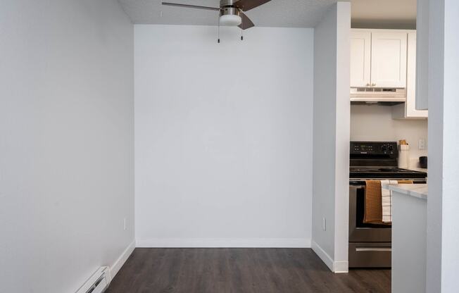 a kitchen with white walls and a stove and a ceiling fan