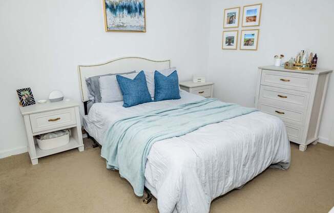 A bedroom with a bed, nightstand, and a painting on the wall.