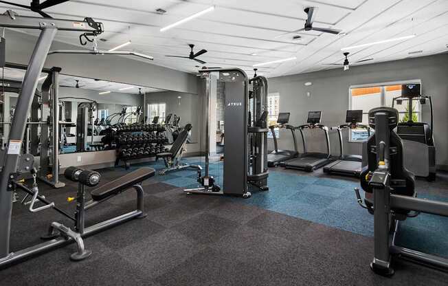 A gym with a variety of equipment including treadmills, weights, and exercise machines.