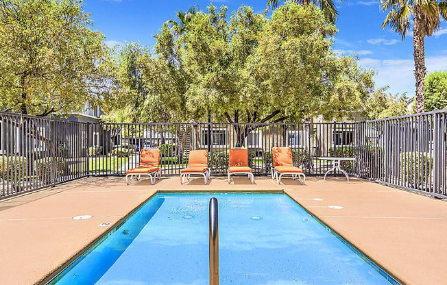 a swimming pool with chairs and a fence