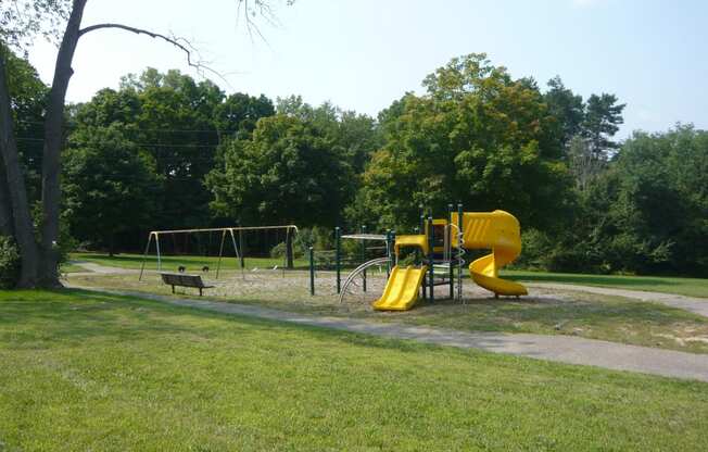 Playscape area in a park with trail and trees