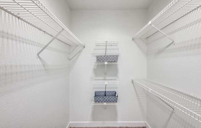 a walk in closet with white walls and shelves and two closets