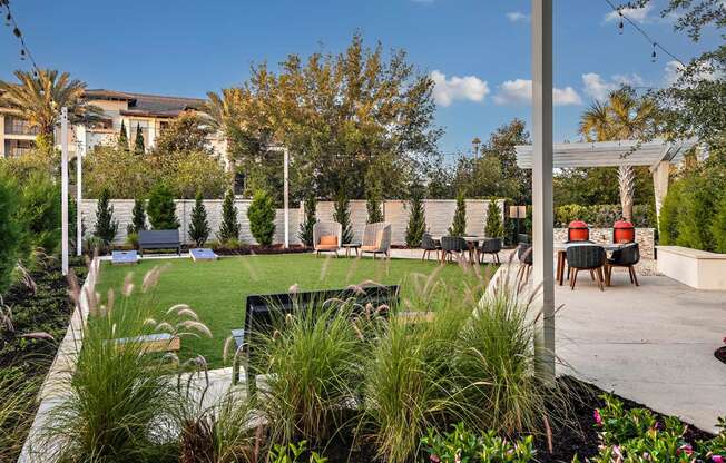 a backyard with a lawn and tables and chairs