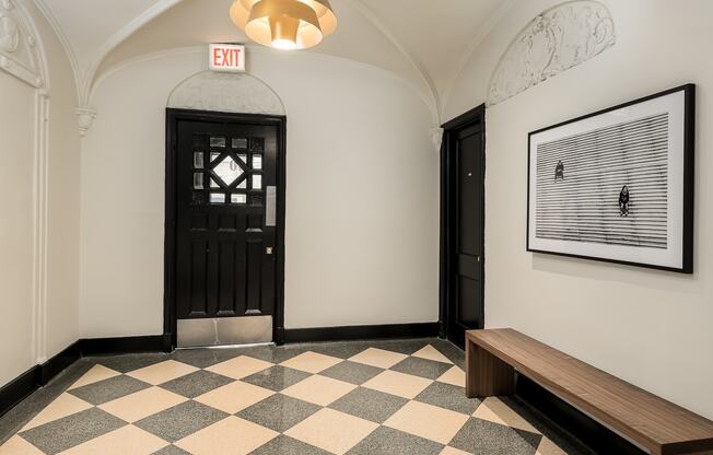 a hallway with a black door and a bench and a checkerboard floor