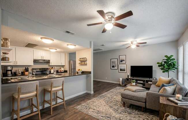 A well-lit kitchen and living room with a ceiling fan.
