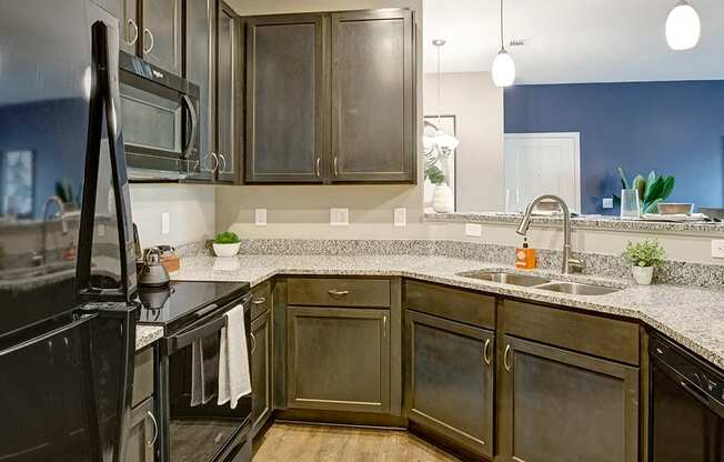 Kitchen with dark cabinets, black appliances, sink , granite countertops, and light hard wood flooring at Ascent at Mallard Creek Charlotte, NC