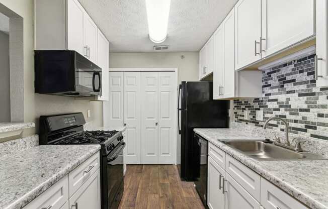 Apartment kitchen with white cabinets and black appliances at Oakley Run apartments in Smyrna, GA