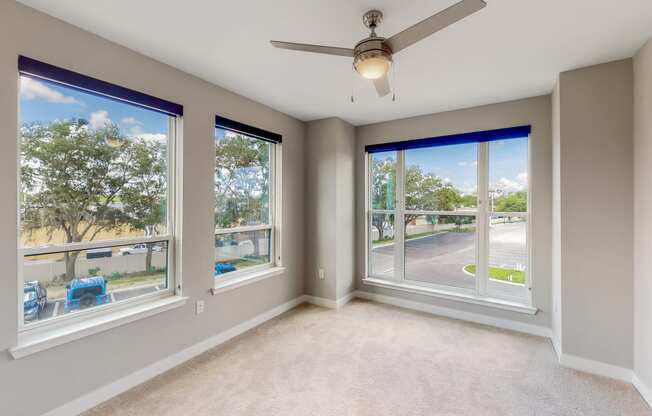 a bedroom with a ceiling fan and large windows