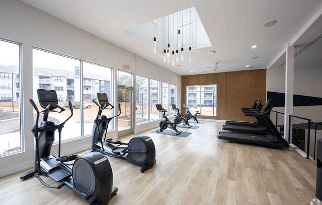 A gym with treadmills, exercise bikes and a wooden floor.