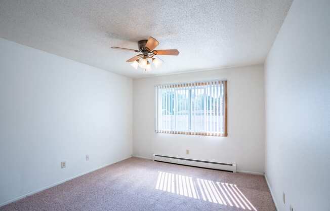 a bedroom with a ceiling fan and a window. Fargo, ND Betty Ann Apartments