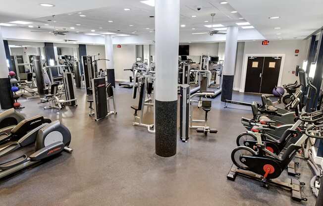 A gym with a variety of equipment including treadmills, weights, and exercise machines.