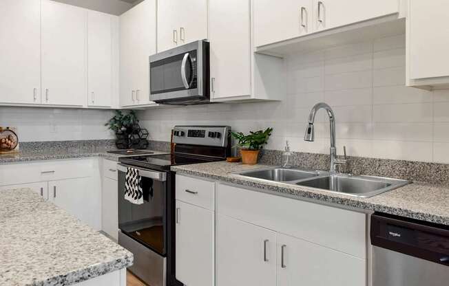 A kitchen with white cabinets and a granite countertop.