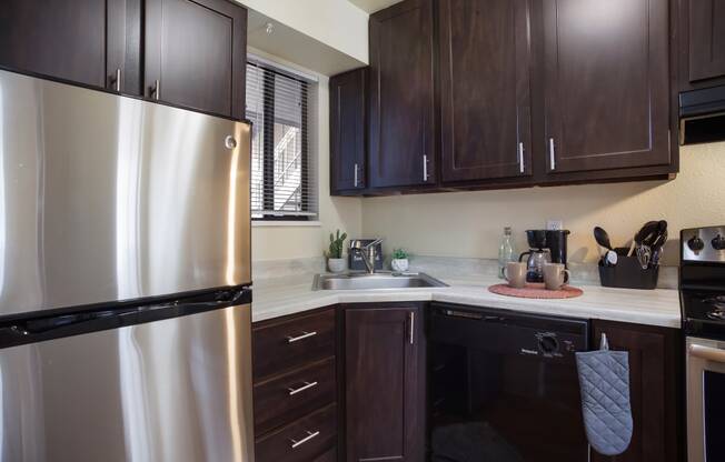 Kitchen with stainless steel appliances and dark wood cabinets  at Governor's Park, Fort Collins, 80525