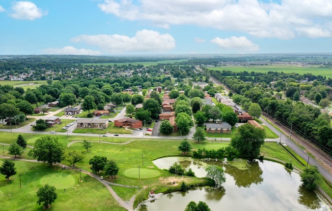 A flooded park with a pond in the middle and houses in the background.