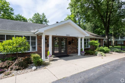 the front of a brick house with a porch and a driveway