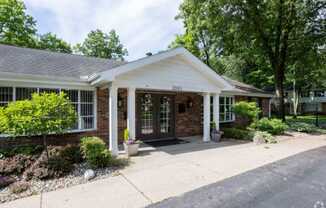 the front of a brick house with a porch and a driveway