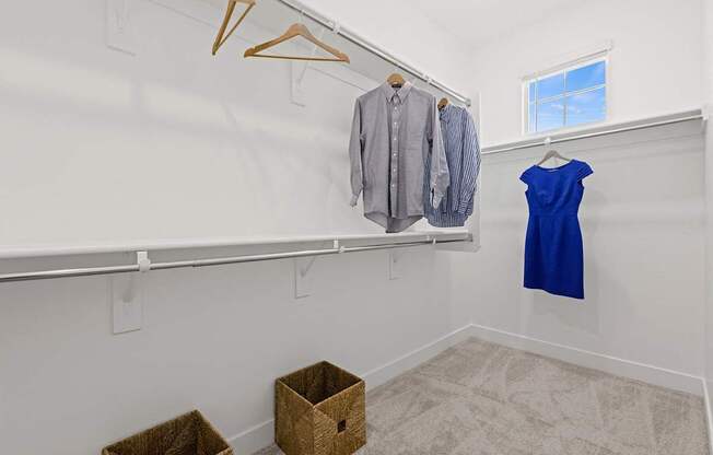 A room with a clothes rack and two baskets on the floor.