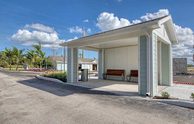 A small white building with a porch and a bench in front.