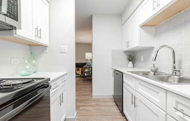 A kitchen with white cabinets and a stove top oven.