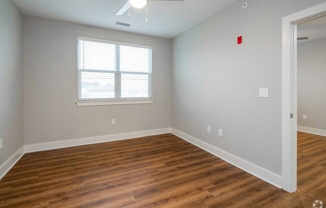 an empty living room with wood floors and a window