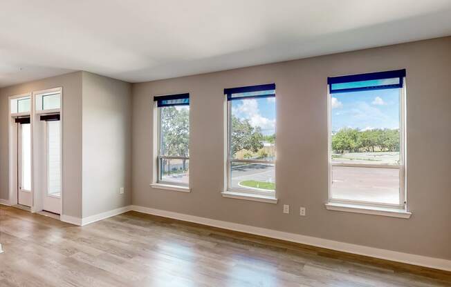 an empty room with hardwood floors and four windows