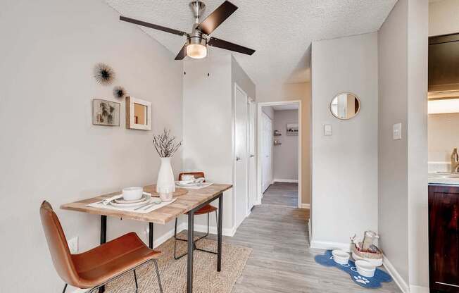 A dining room with a brown chair and a table with a vase of flowers on it at Mountain Vista Apartments, Lakewood