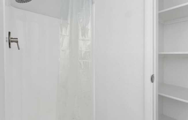 A white shower curtain is hanging in a white bathroom.