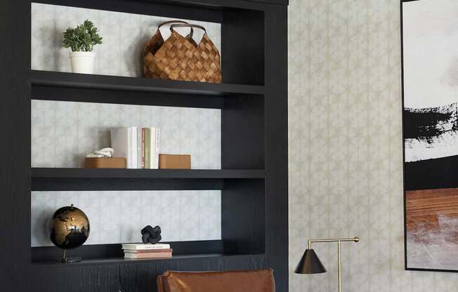 A brown leather chair sits in front of a shelf with a plant and a globe on it.