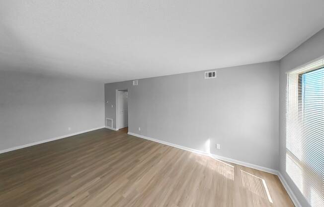 an empty living room with wood flooring and a large window