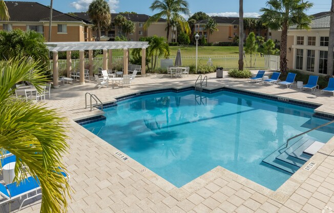 A pool surrounded by a patio and palm trees.