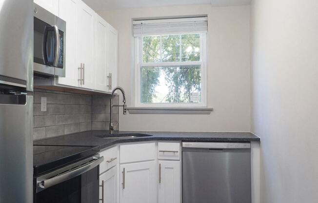 an empty kitchen with white cabinets and a black counter top  at Enclave West Hartford / Parc West, Connecticut