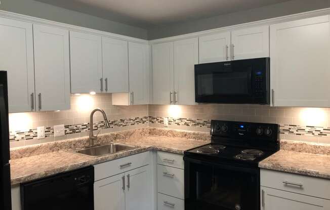a kitchen with white cabinets and black appliances