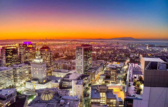 A cityscape at dusk with buildings illuminated against a twilight sky.