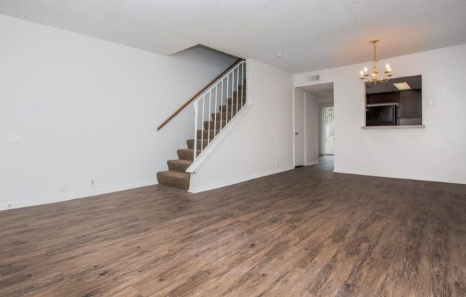 an empty living room with white walls and a staircase