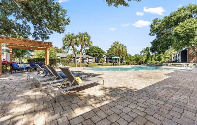 a swimming pool with chaise lounge chairs and trees