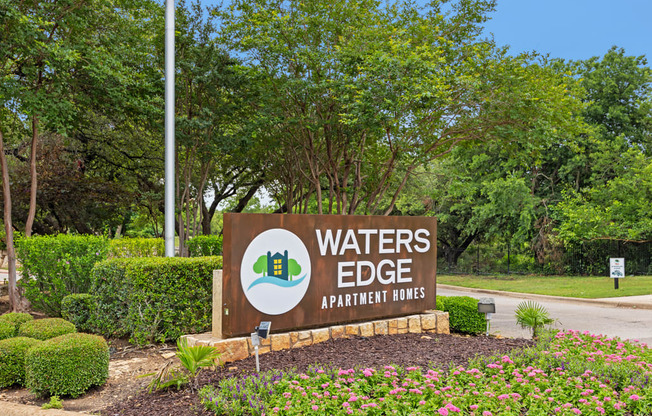 a sign that says waters edge apartments with trees in the background