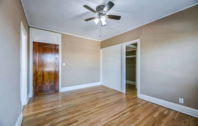 A room with a ceiling fan and wooden floors.