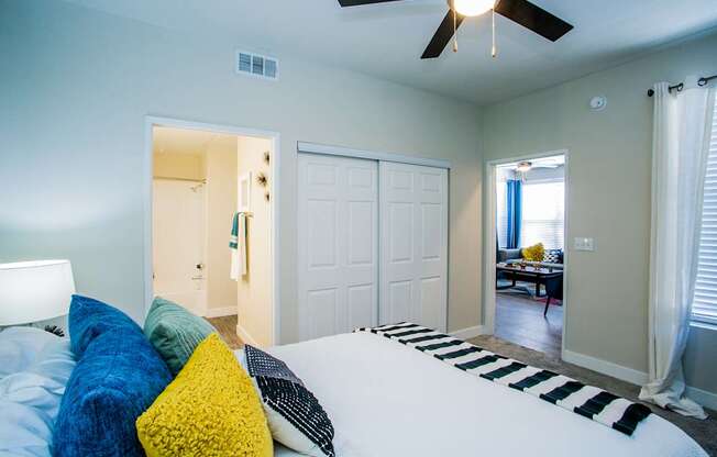 A bedroom with a bed, pillows, and a ceiling fan.