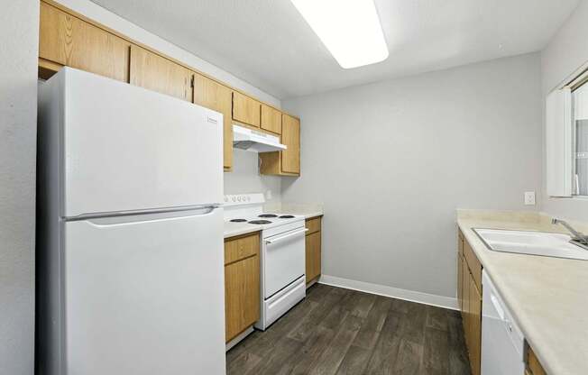 A kitchen with a white refrigerator, wooden cabinets, and a white dishwasher.
