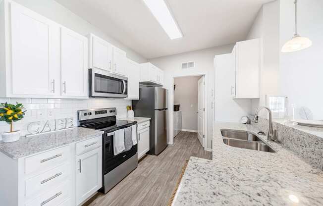 A kitchen with white cabinets and a granite countertop.