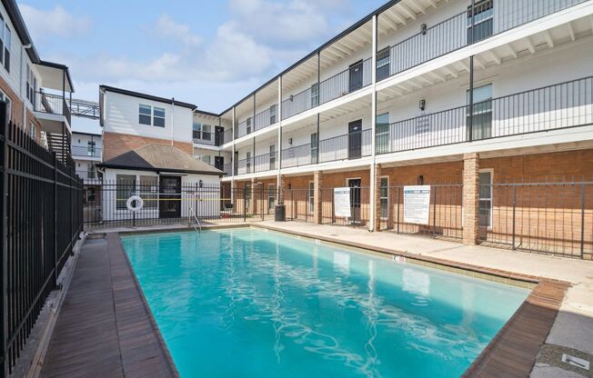 the pool is next to a building with a fence around it