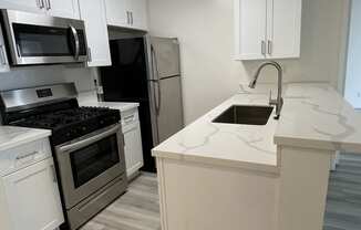 Kitchen with Hardwood Floors, White Cabinets and Stainless Steel Appliances