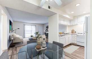 a living room with a glass table and a kitchen in the background at Redlands Park Apts, Redlands, CA